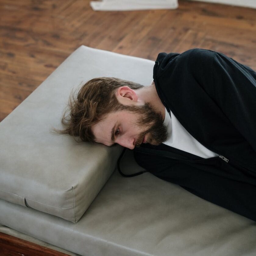 man in black long sleeve shirt lying on gray couch