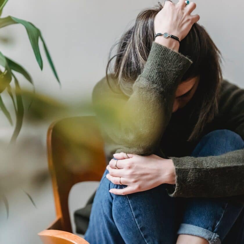 unrecognizable upset lady embracing knees sitting on chair